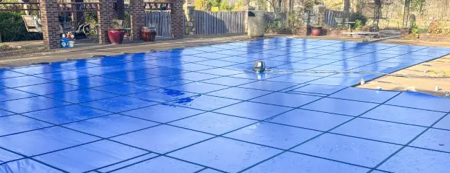 Blue solid vinyl safety cover on a True-L shaped pool