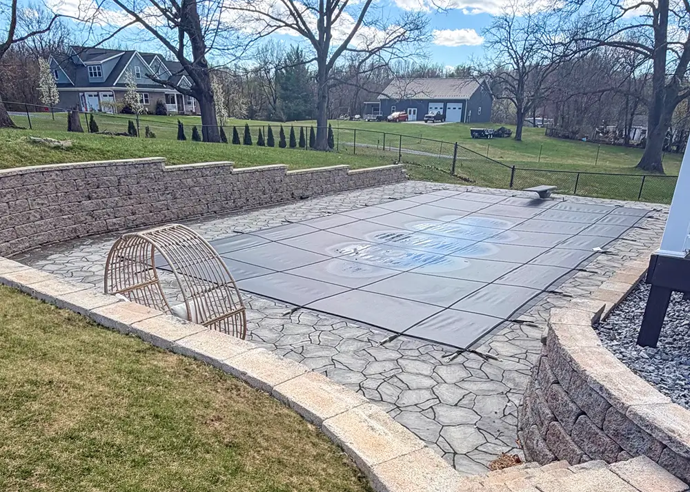 Inground pool with a tan mesh safety cover