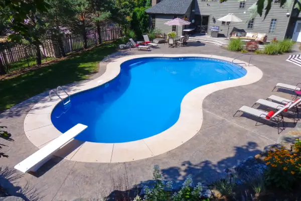 Freeform vinyl liner pool with a paved deck